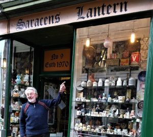 A photo of a man standing outside and pointing towards a shop named 'Saracens Lantern'