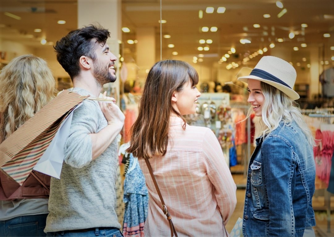A photo of three young adults shopping together and smiling