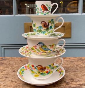 A photo of four stacked cups and saucers, each with small birds on them