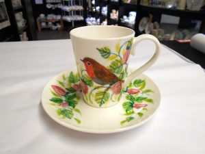 A photo of a cup and saucer with a robin on it